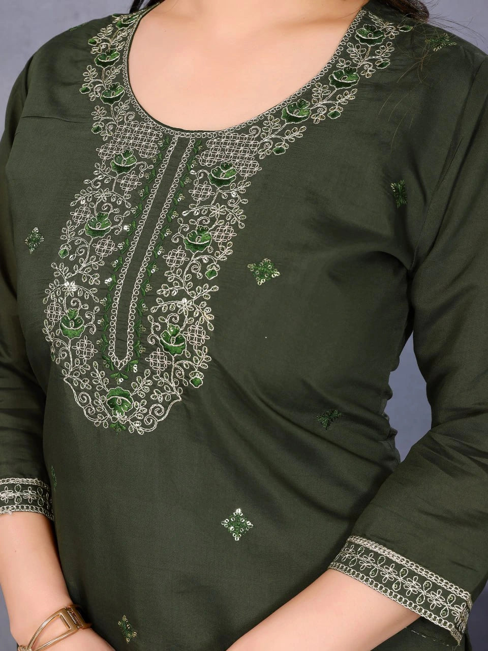 Green embroidered top with intricate patterns on a plain background